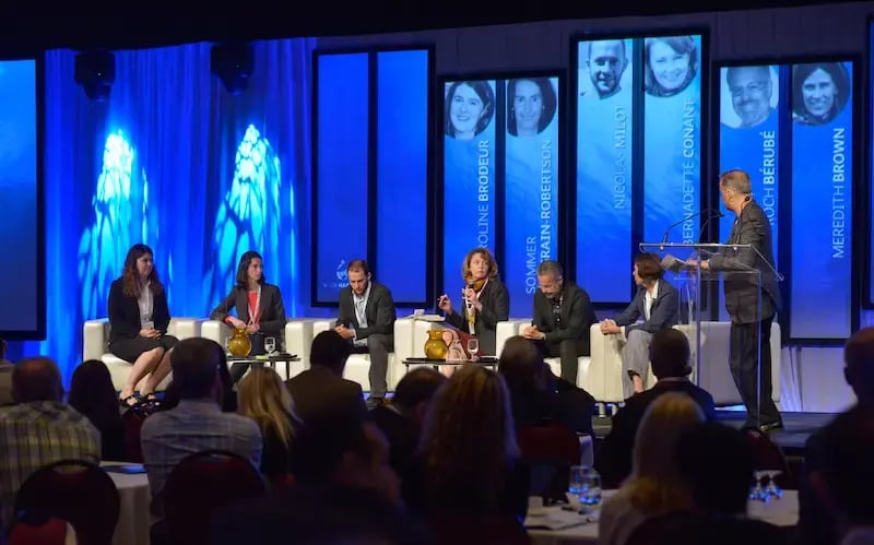 Six panelists sit on white sofas during the AquaHacking Ottawa River 2015 event. Large vertical screens behind them display their names and portraits, including Caroline Brodeur and Nicolas Milot. A moderator stands at a glass lectern to the right, facing the engaged audience.