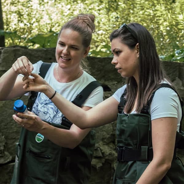 Researchers examining water samples outdoors, emphasizing hands-on conservation efforts.