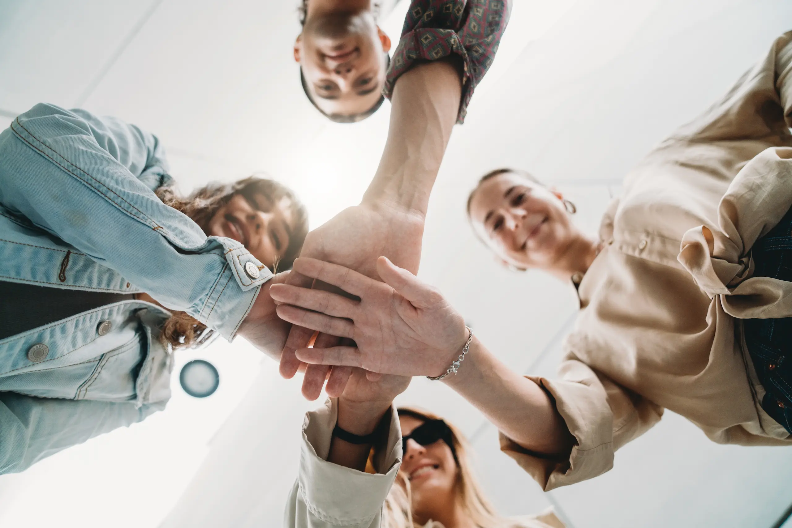 A diverse group of individuals joins hands in a circle, symbolizing teamwork.