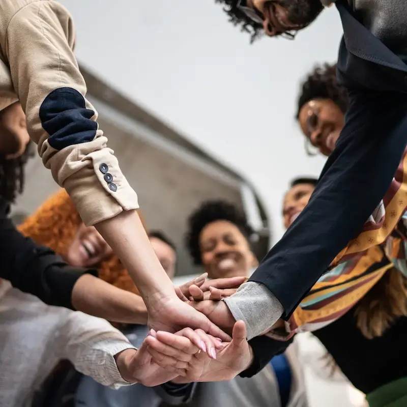 Diverse group of people joining hands in a circle.