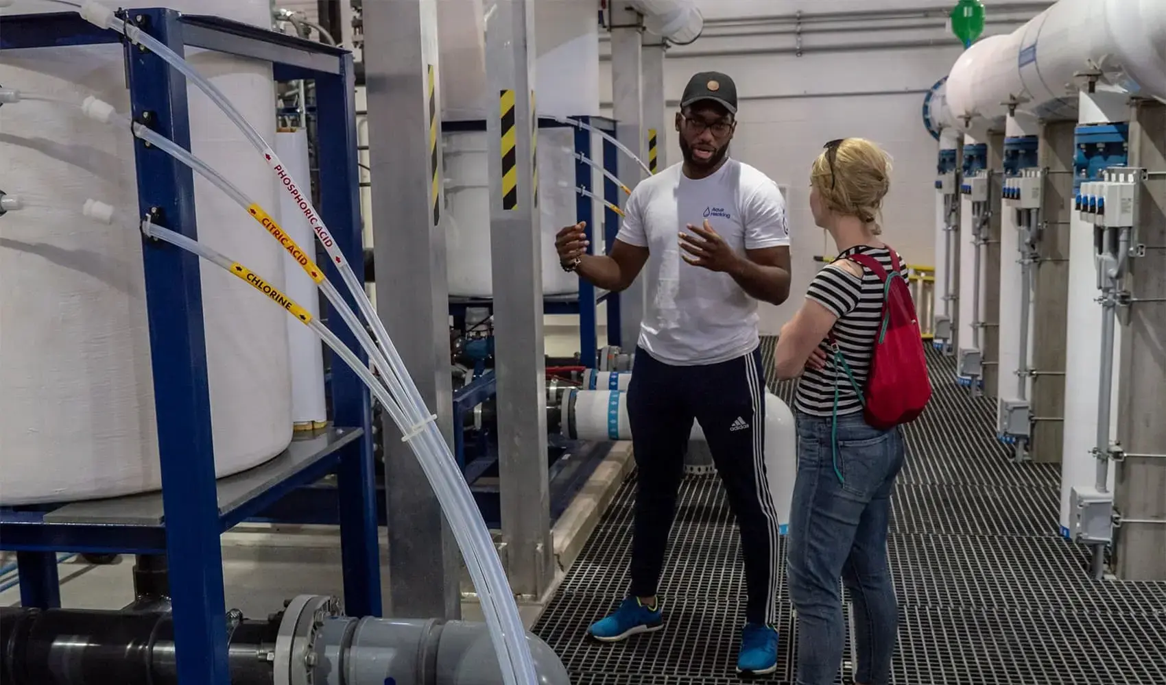 An engineer explains water purification processes to a visitor at a treatment facility.