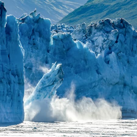 A massive chunk of ice breaking off a glacier and crashing into the water, illustrating the effects of rising global temperatures and climate change on polar and glacial regions. A massive chunk of ice breaking off a glacier and crashing into the water, illustrating the effects of rising global temperatures and climate change on polar and glacial regions.