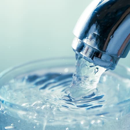 Fresh and clear water flowing from a chrome faucet into a glass, highlighting the importance of safe and accessible drinking water. Fresh and clear water flowing from a chrome faucet into a glass, highlighting the importance of safe and accessible drinking water.