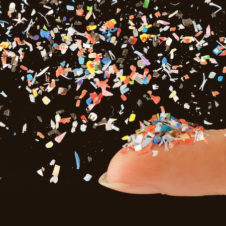 A close-up of a fingertip covered in tiny, colorful microplastic particles, illustrating the widespread pollution of water and ecosystems. A close-up of a fingertip covered in tiny, colorful microplastic particles, illustrating the widespread pollution of water and ecosystems.